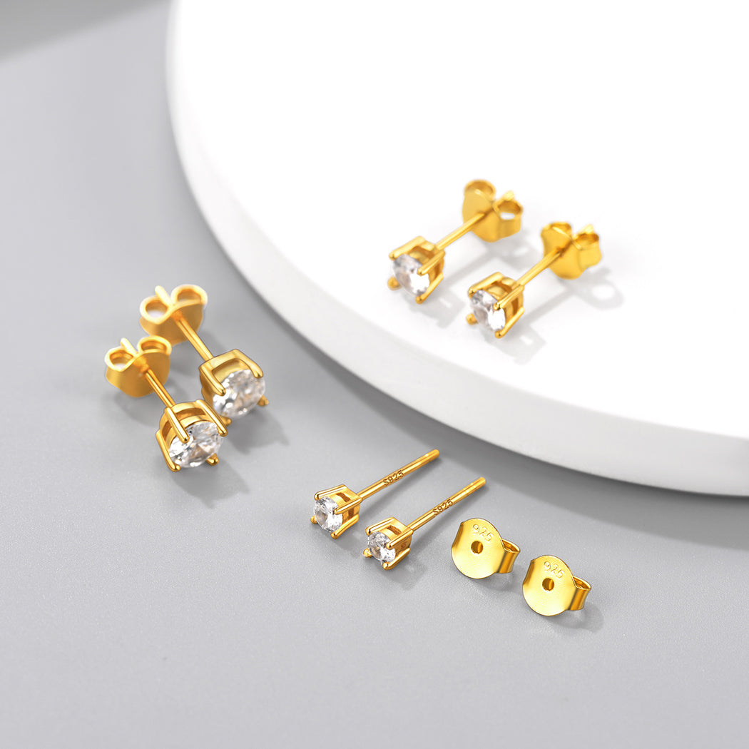 Gold stud earrings with clear gemstones on a light gray background