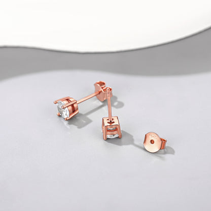 Rose gold earrings with clear gemstones on a light gray background