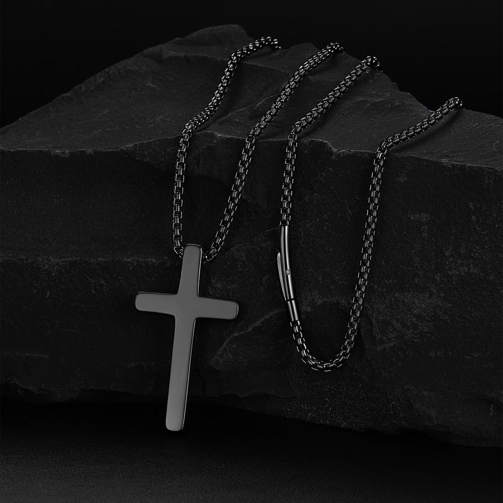 Silver cross pendant on a chain against a dark stone background
