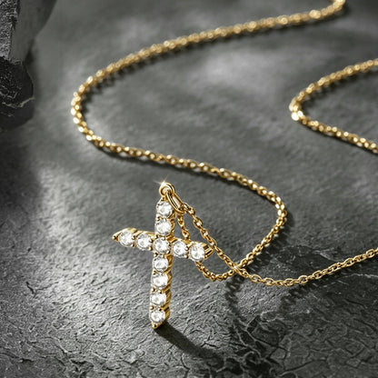 A gold cross pendant necklace adorned with clear crystals.