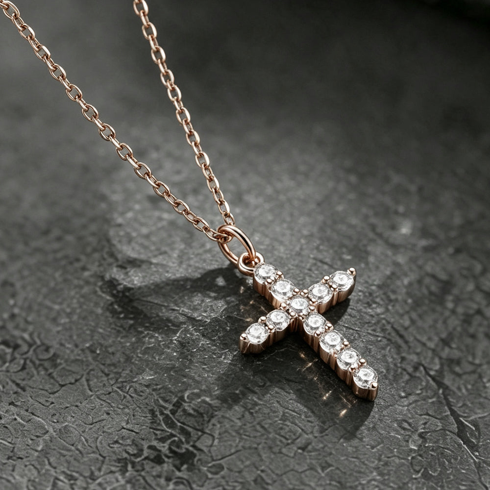 A rose gold cross pendant necklace adorned with small clear stones.