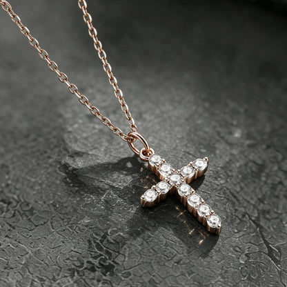 A rose gold cross pendant necklace adorned with small clear stones.