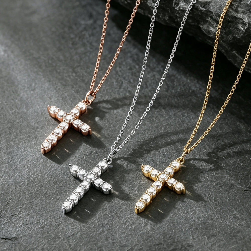 Three cross-shaped pendant necklaces with CZ stones, shown in rose gold, silver, and yellow gold tones on dark textured stone.