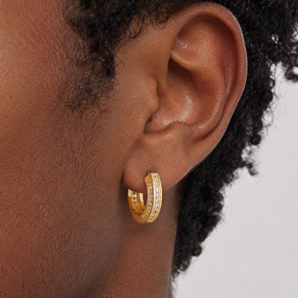 Man wearing gold cubic zirconia hoop earrings