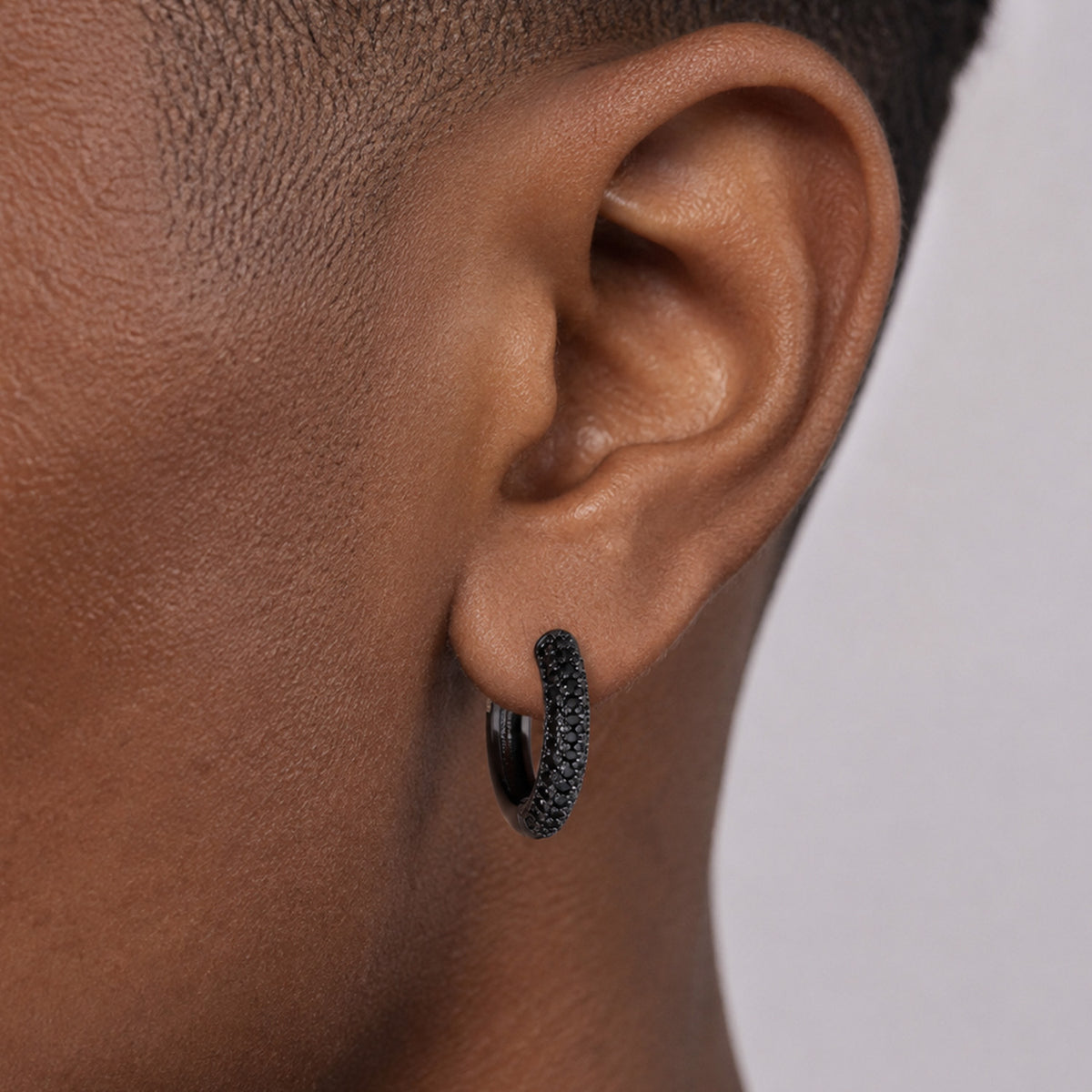 Close-up of black cubic zirconia hoop earring on ear
