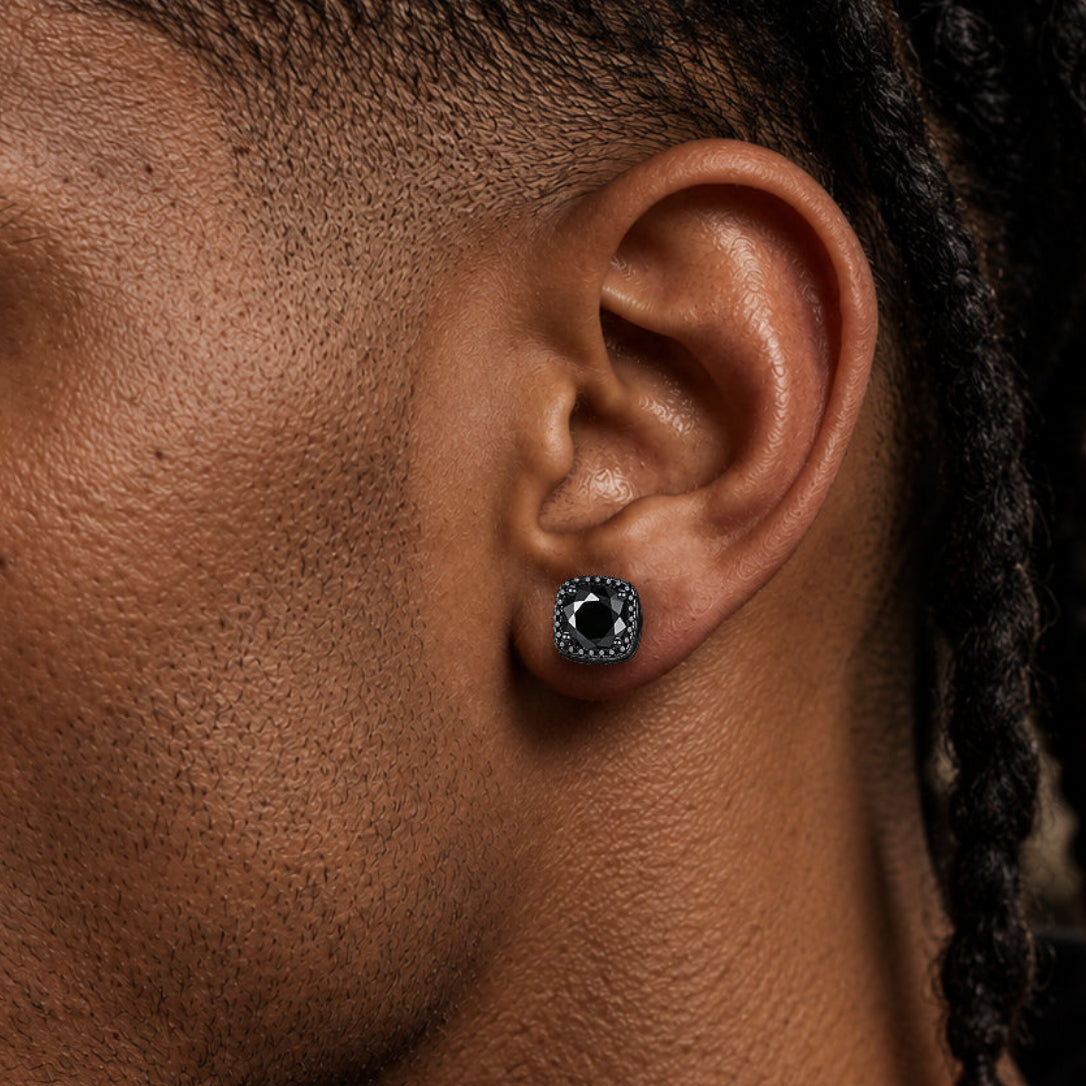 Close-up of a man's ear wearing a black circular stud earring with a silver-toned textured halo.