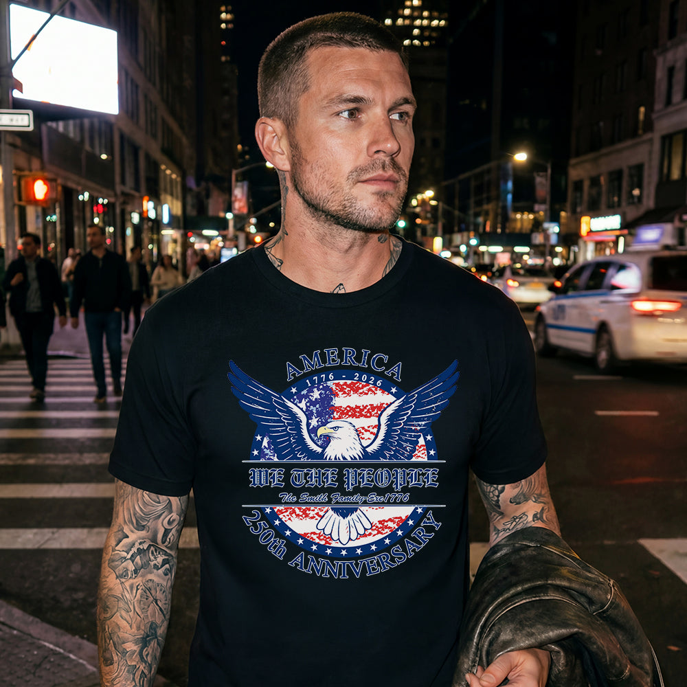 Man wearing a black USA bald t-shirt with an eagle graphic and text on a city street at night.