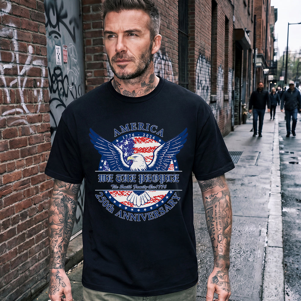 Man wearing a black t-shirt with an eagle graphic and text, standing on a street.