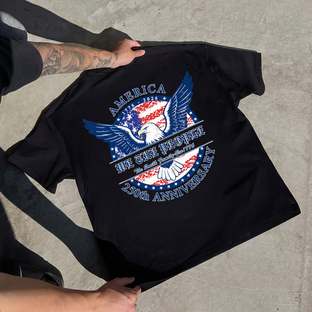 Black t-shirt with a patriotic design featuring an eagle and text, held by a person on a concrete surface.