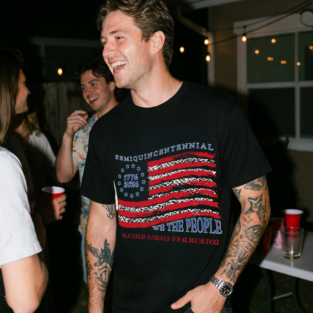 A man wearing a black USA Flag Patriotic T-Shirt with a graphic design, standing in a social setting.