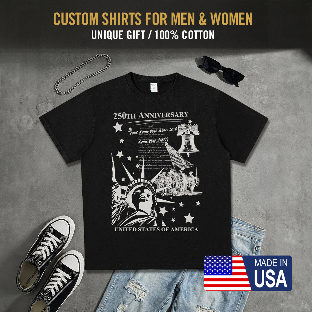 Black t-shirt with 250th Anniversary design, sunglasses, sneakers, and jeans on a gray surface.