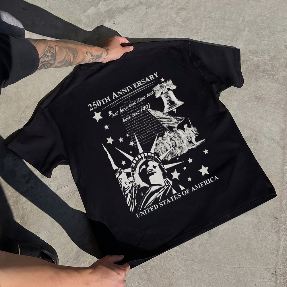 Black t-shirt with white graphic design held by a person on a concrete surface