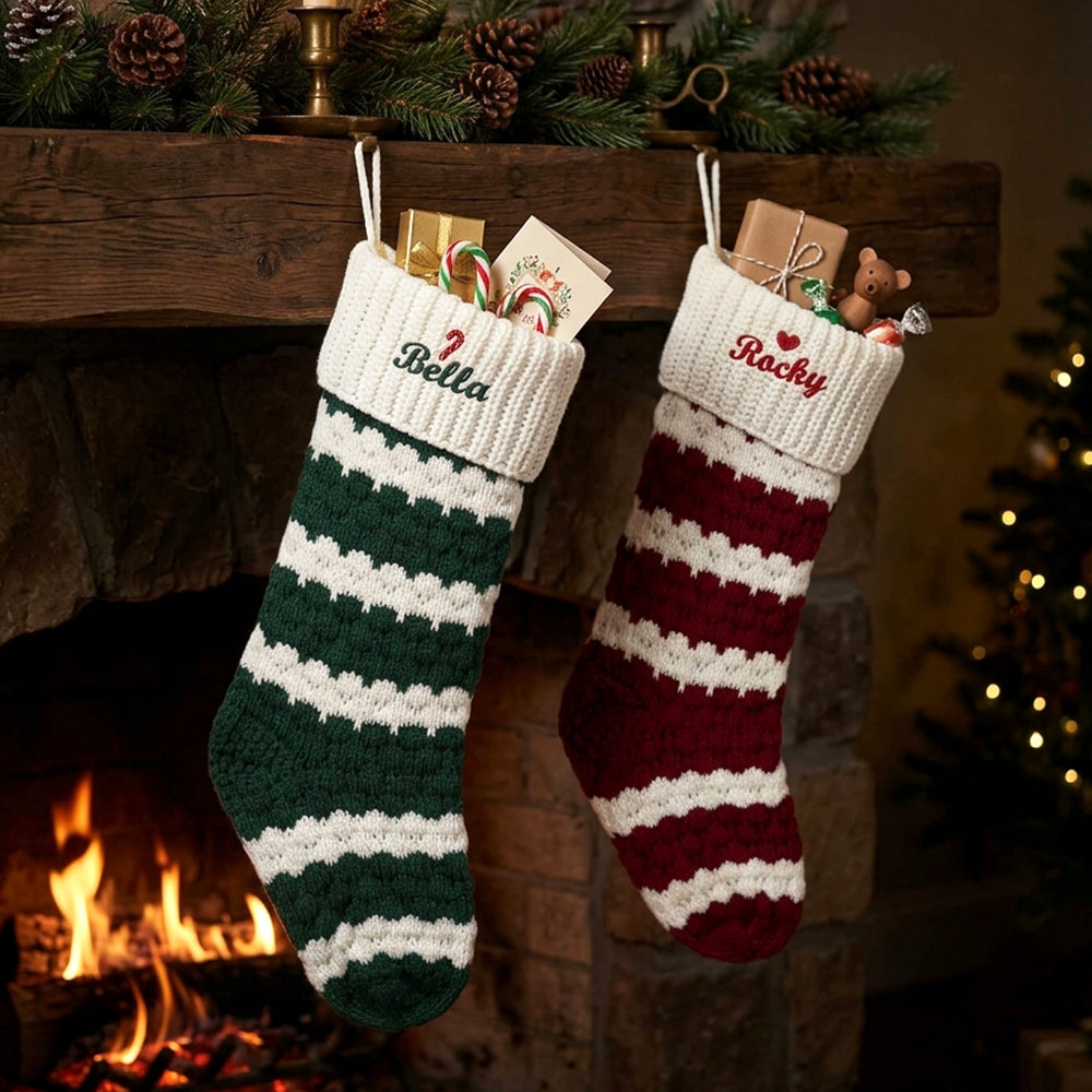 Two personalized crocheted Christmas stockings hanging from a fireplace mantel with holiday decorations in the background.