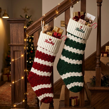 Two personalized Christmas stockings hang from a wooden staircase railing in a decorated home.