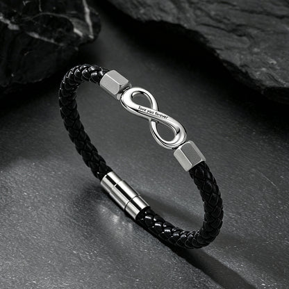 Close-up of infinity knot charm and custom engraving on braided leather bracelet