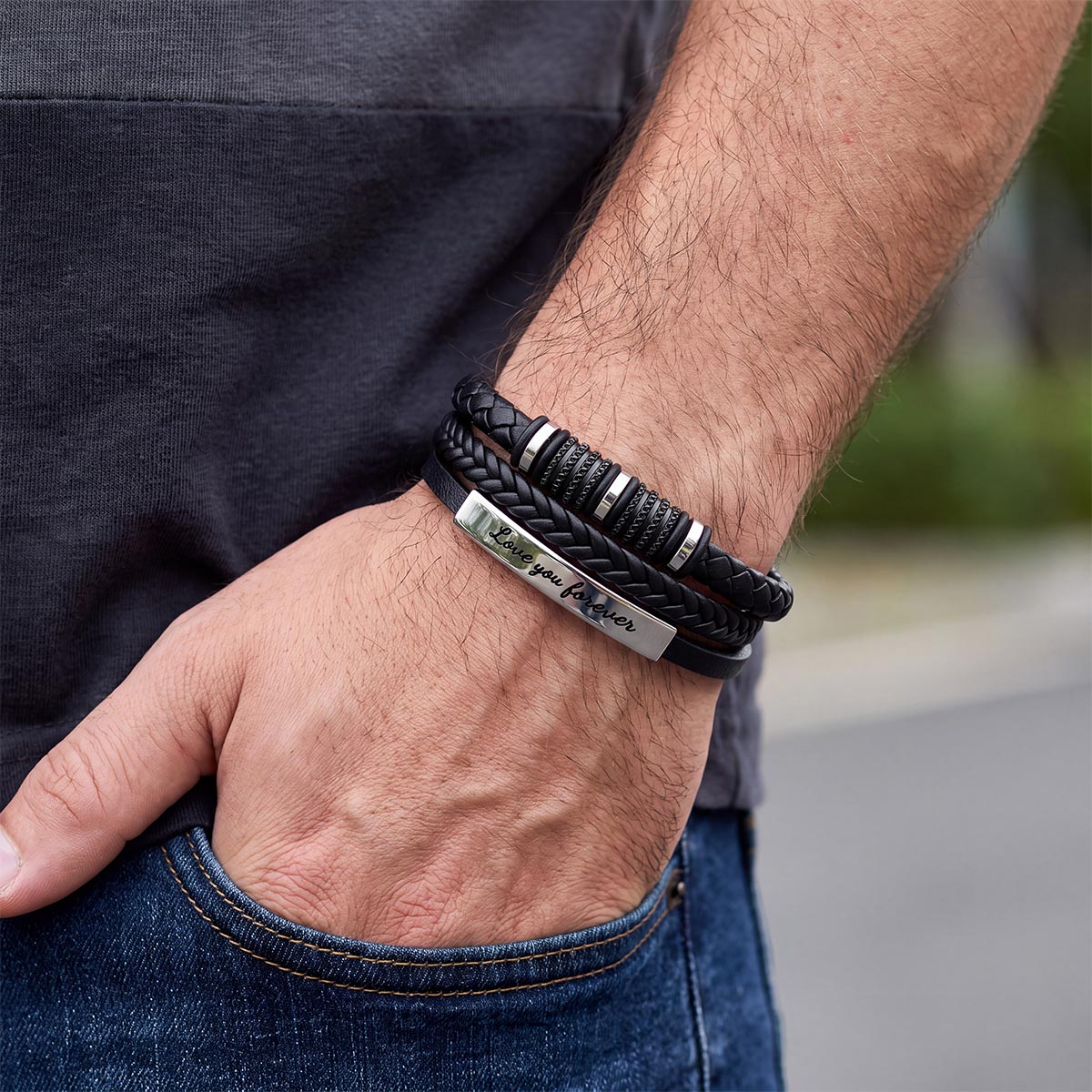 A close-up of a man's wrist wearing a multi-layered bracelet set.