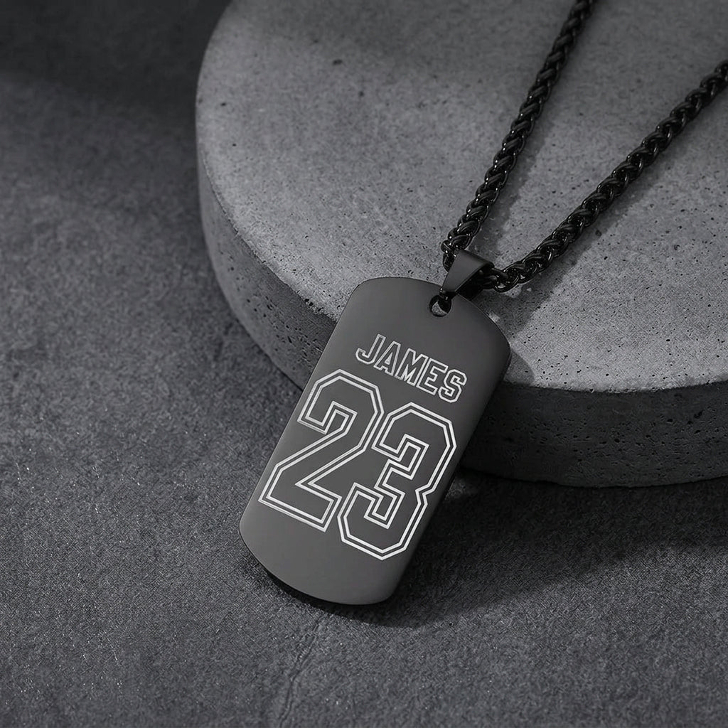 A black dog tag necklace engraved with the name and the number.