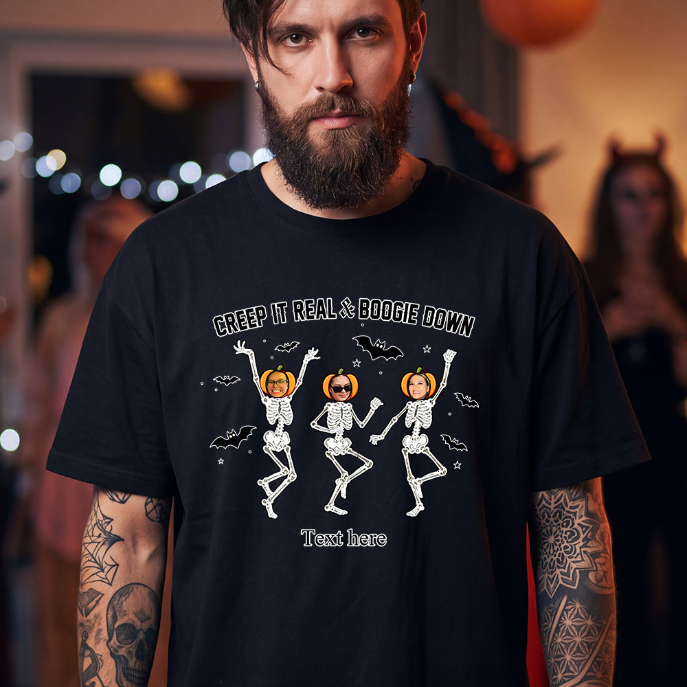 A man wearing a black graphic t-shirt with a Halloween design of three dancing skeletons and pumpkins. 