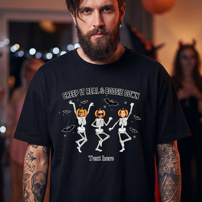 A man wearing a black graphic t-shirt with a Halloween design of three dancing skeletons and pumpkins. 