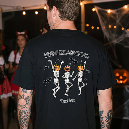 A man wearing a black t-shirt with a Halloween graphic of three dancing skeletons with pumpkins.