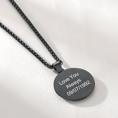 A black round pendant necklace engraved with 'Love You Always 09/07/1992'.background.