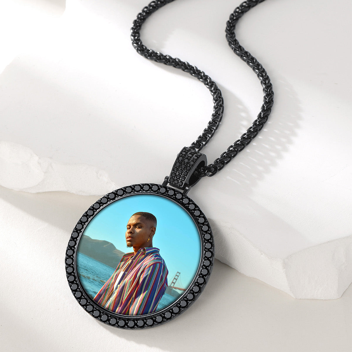 A custom circular pendant necklace in a black bezel with small clear stones.