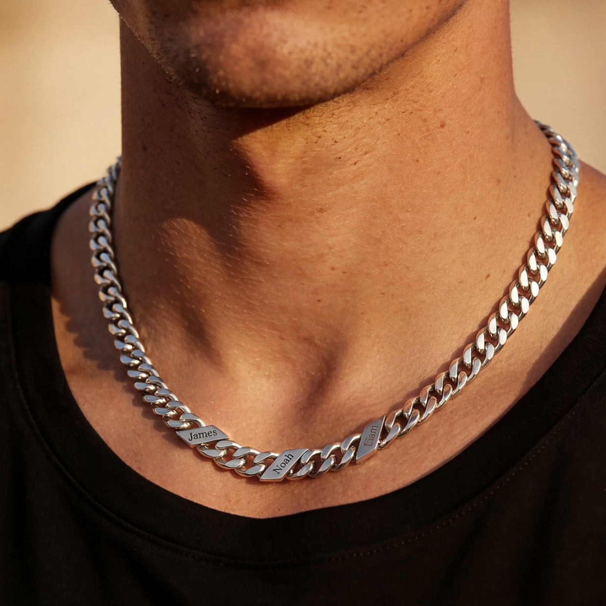 Man wearing a silver name chain necklace with a blurred background