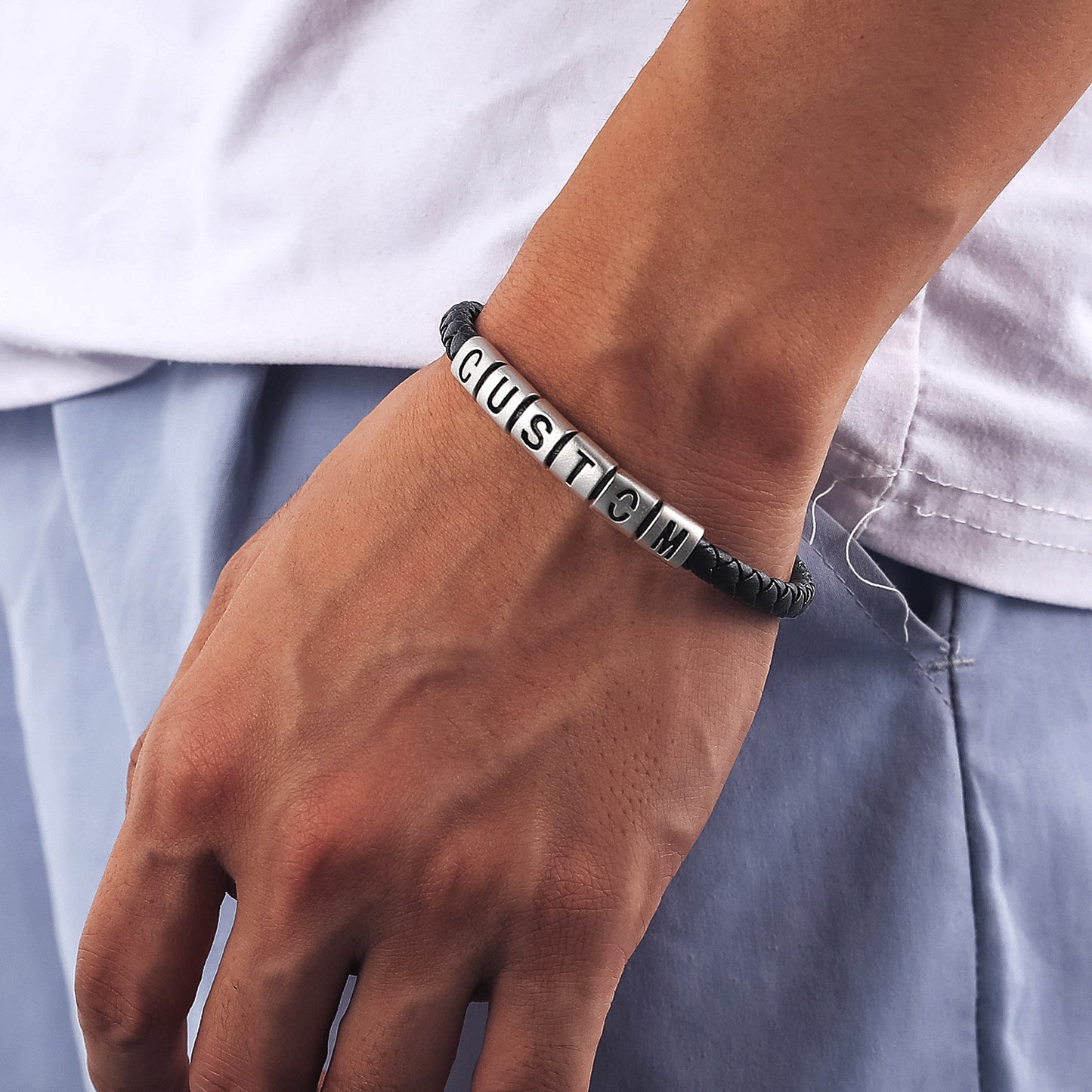 Bracelet with engraved text on a wrist against a neutral background
