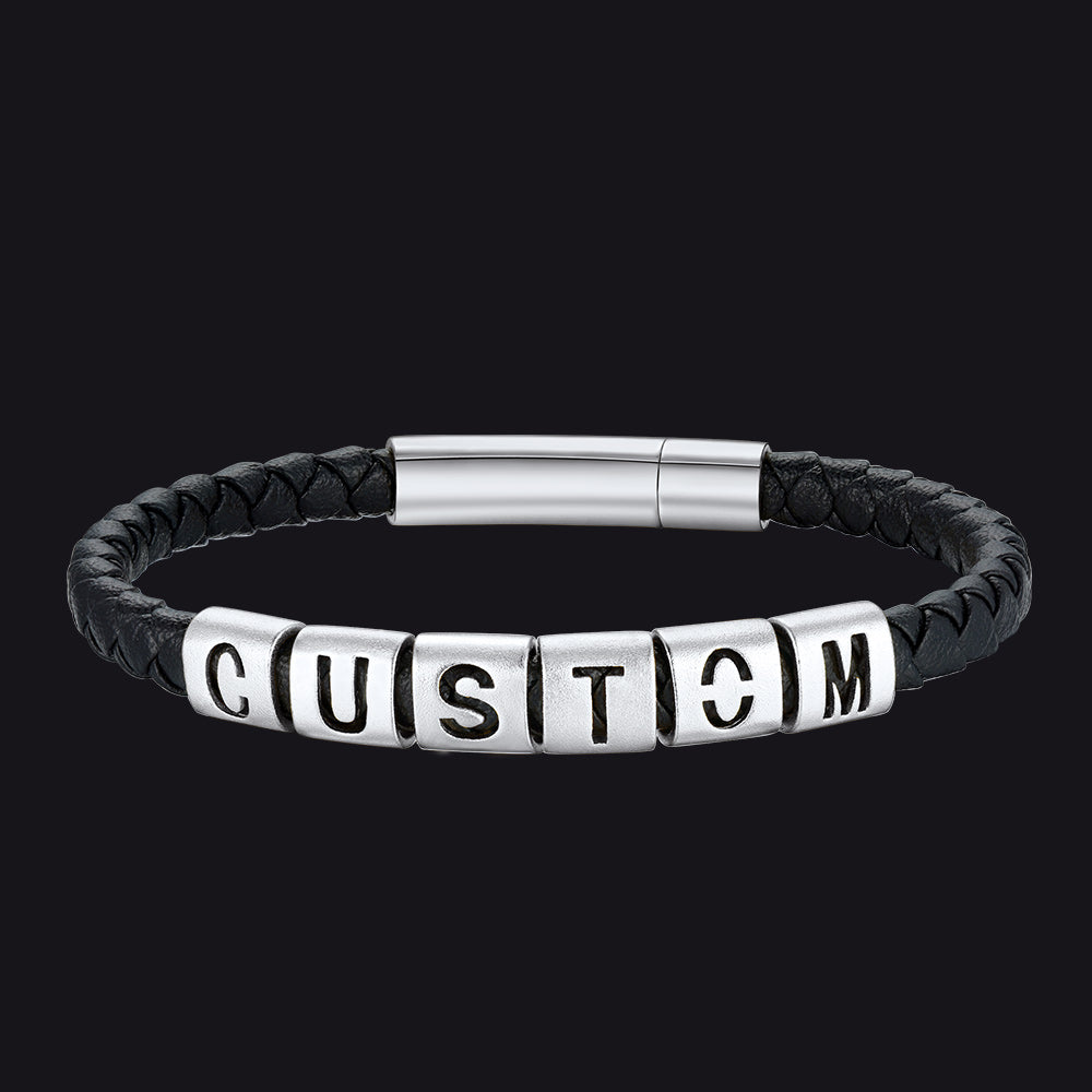 Black leather bracelet with silver beads spelling 'CUSTOM' on a black background