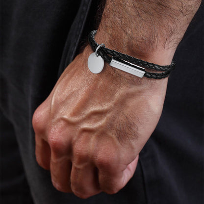 Bracelet with two metal tags on a wrist against a dark background