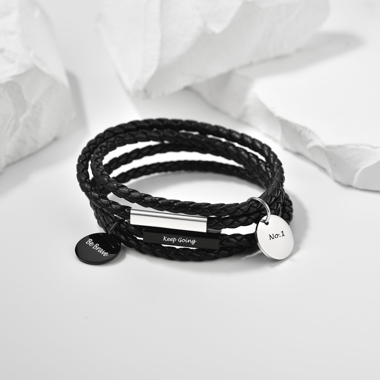 Black braided bracelet with silver tags on a white background