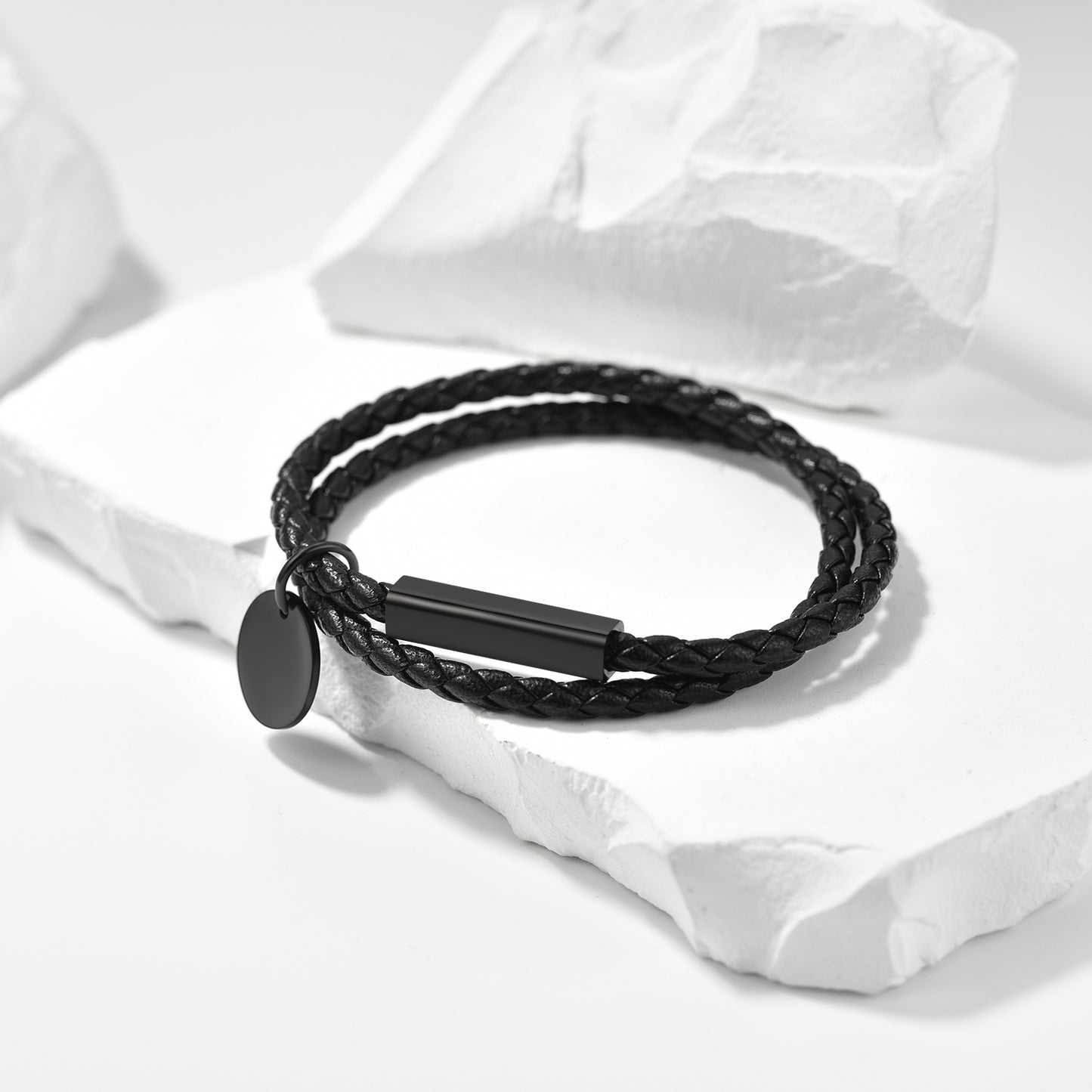 Black braided bracelet with a tag on a white fabric background