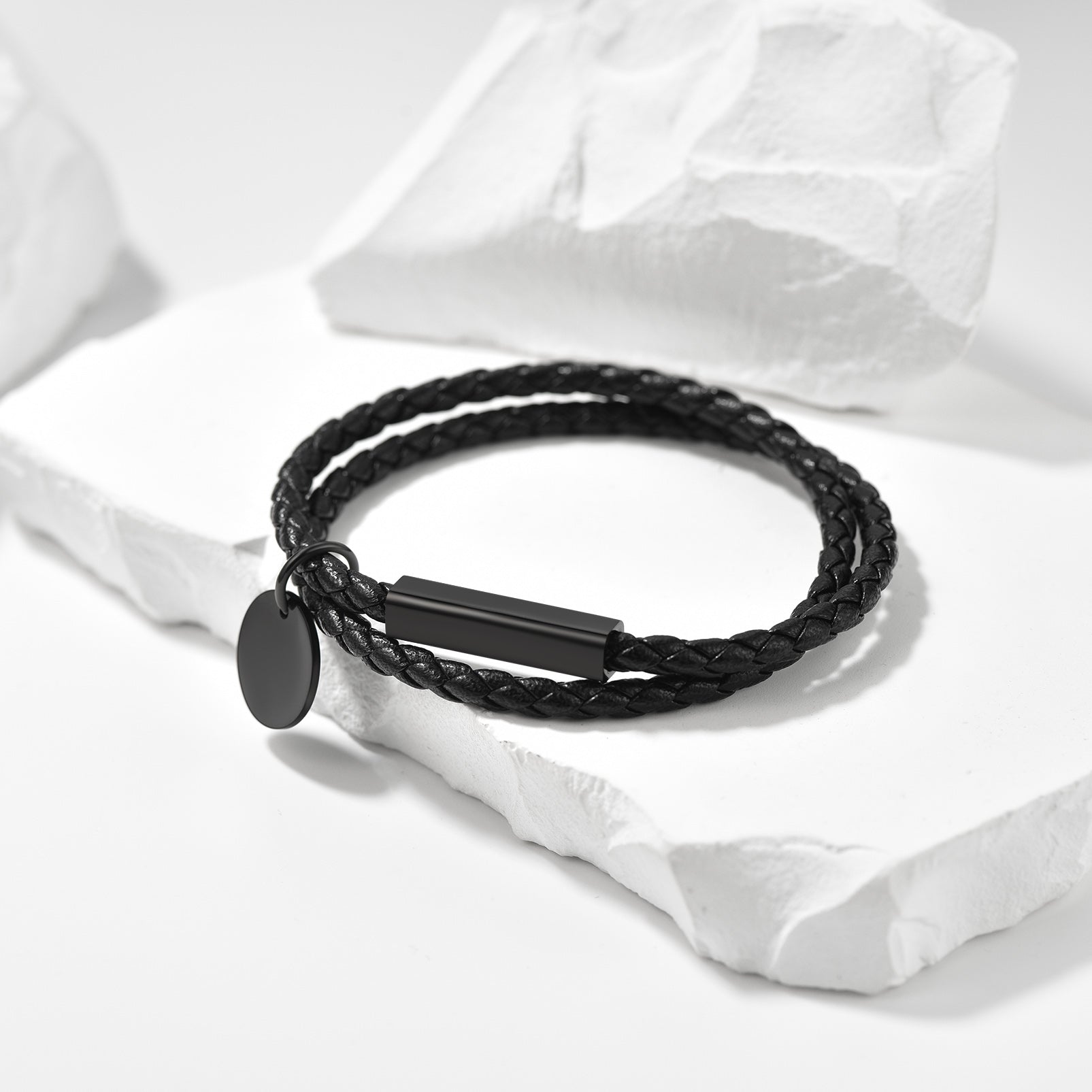 Black braided bracelet with a tag on a white fabric background