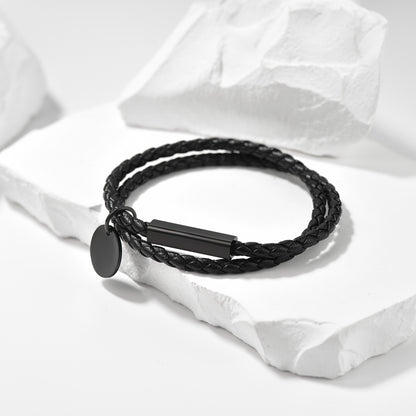 Black braided bracelet with a tag on a white fabric background