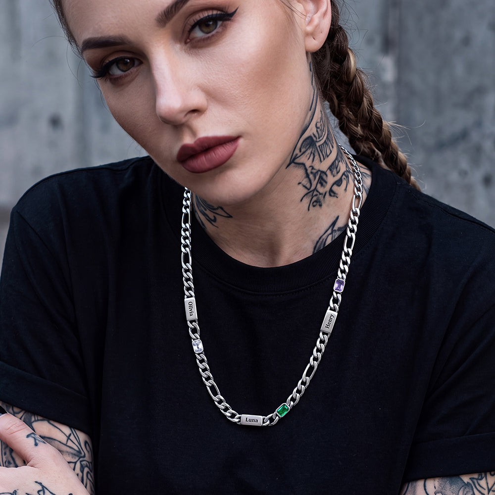A close-up of a woman wearing a silver chain necklace with engraved nameplates and birthstones