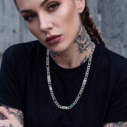 A close-up of a woman wearing a silver chain necklace with engraved nameplates and birthstones