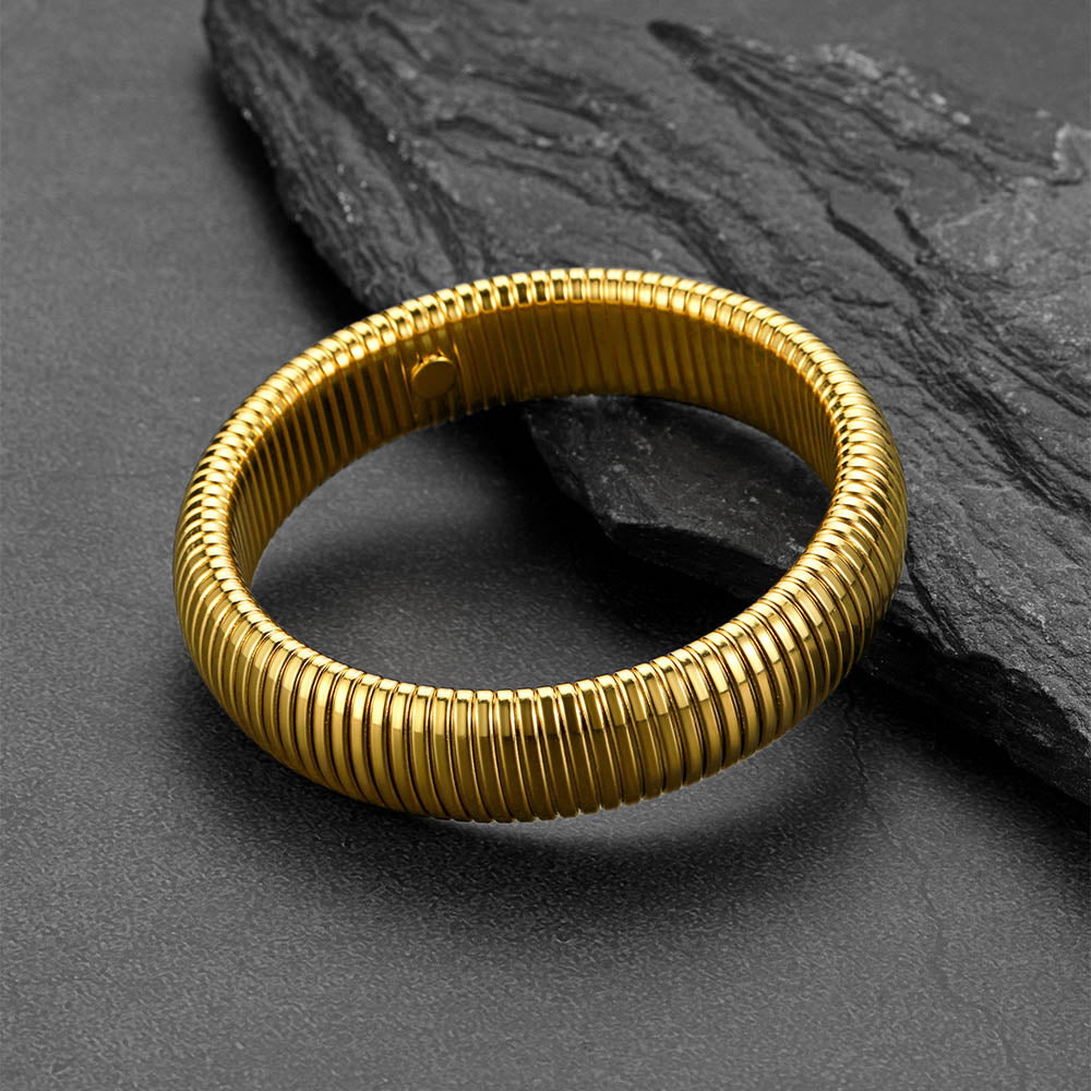 Gold bracelet on a dark stone surface
