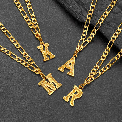 Gold chain necklaces with letter pendants on a dark stone surface