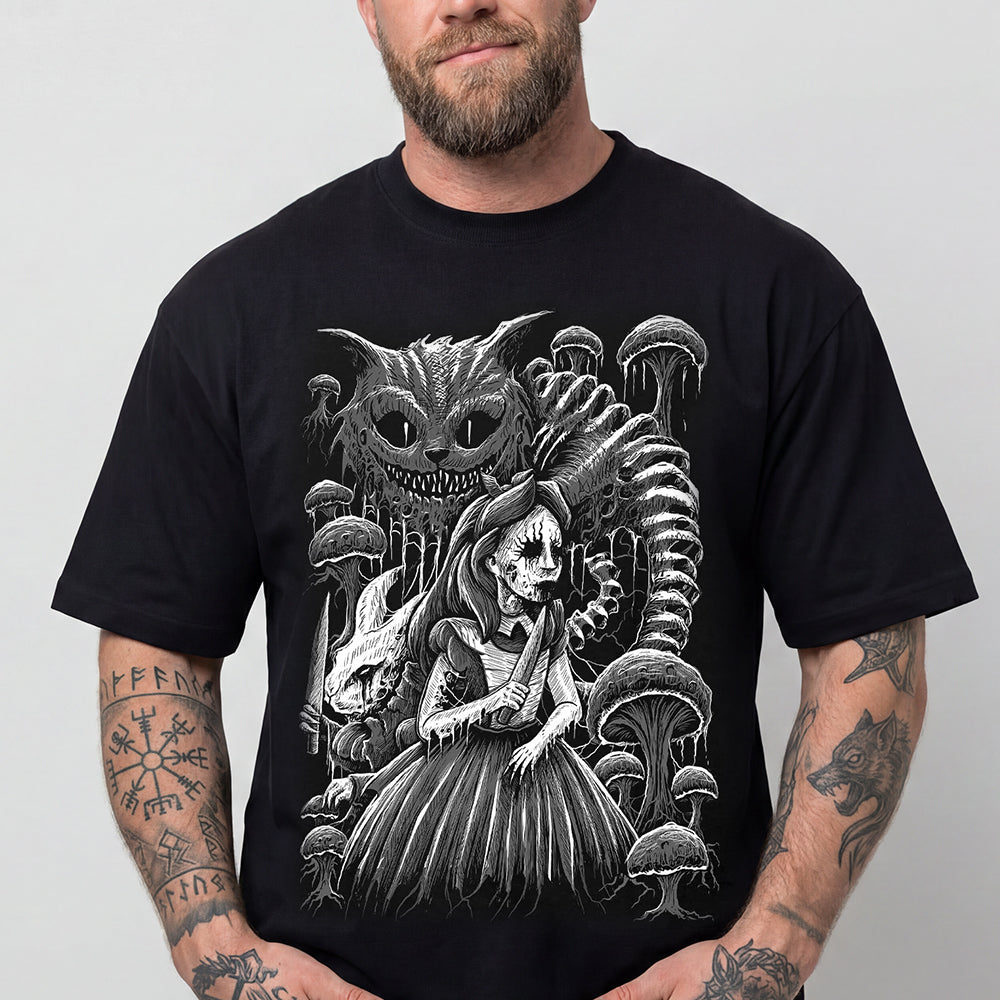 A man wearing a black short-sleeve t-shirt with a detailed black and white graphic print of Alice in Wonderland characters, including the Cheshire Cat and a skeleton figure, against a plain light gray background.