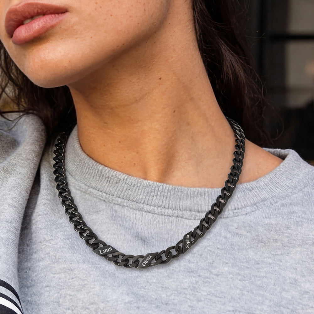 Person wearing a black chain necklace with a blurred background