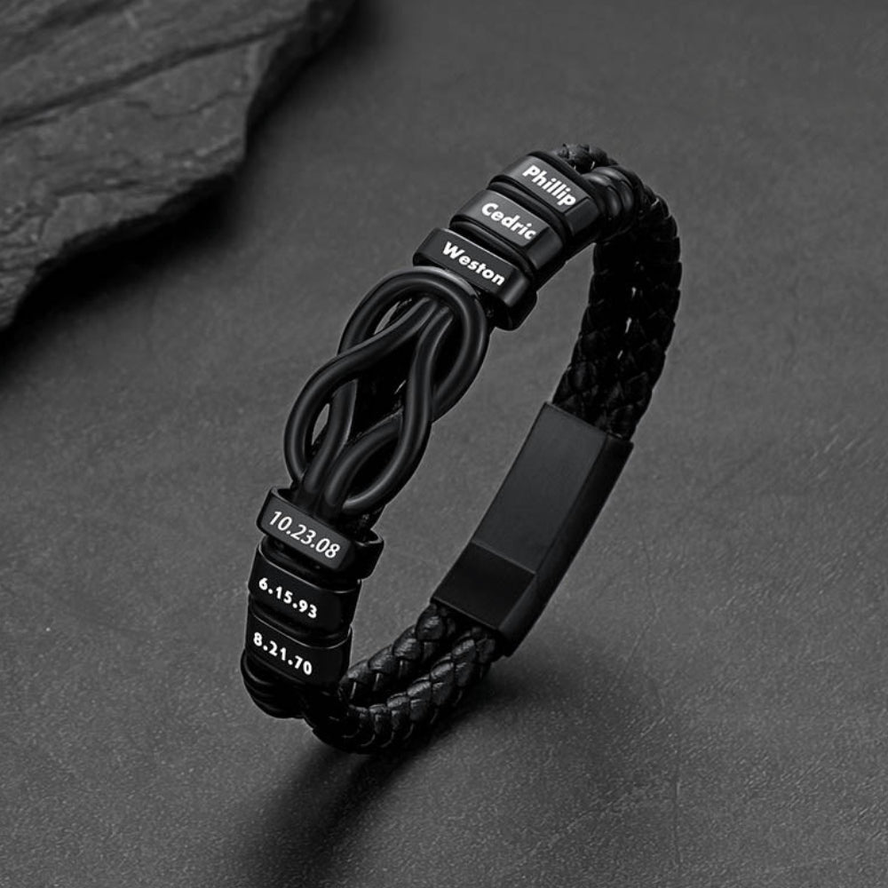 Black braided bracelet with engraved text on a dark stone surface
