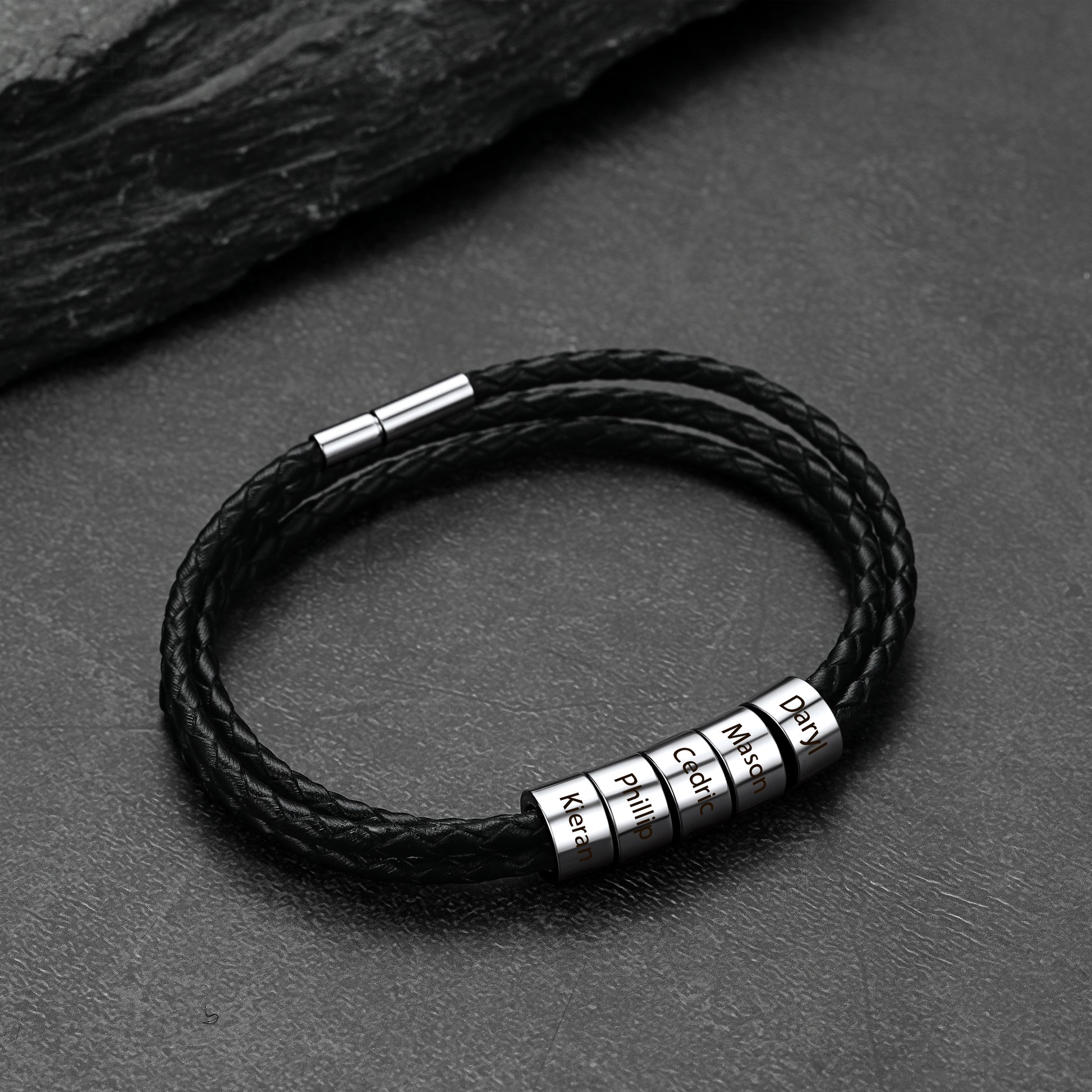 Black braided leather bracelet with metal name beads on a dark surface