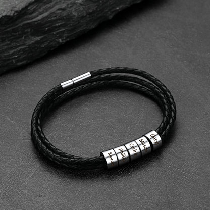 Black braided leather bracelet with metal name beads on a dark surface