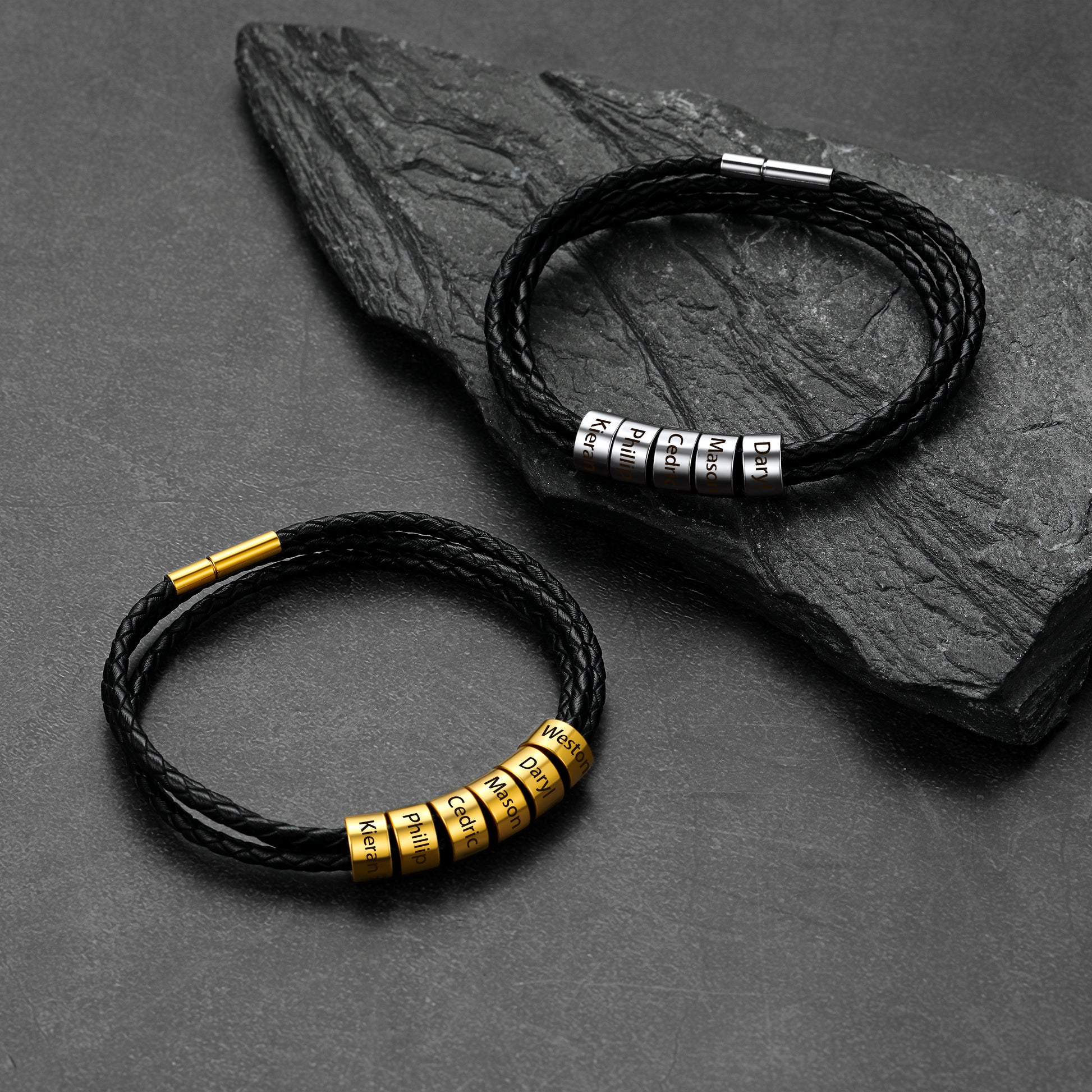 Two black leather bracelets with metal beads on a dark stone surface
