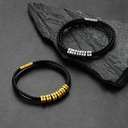 Two black leather bracelets with metal beads on a dark stone surface