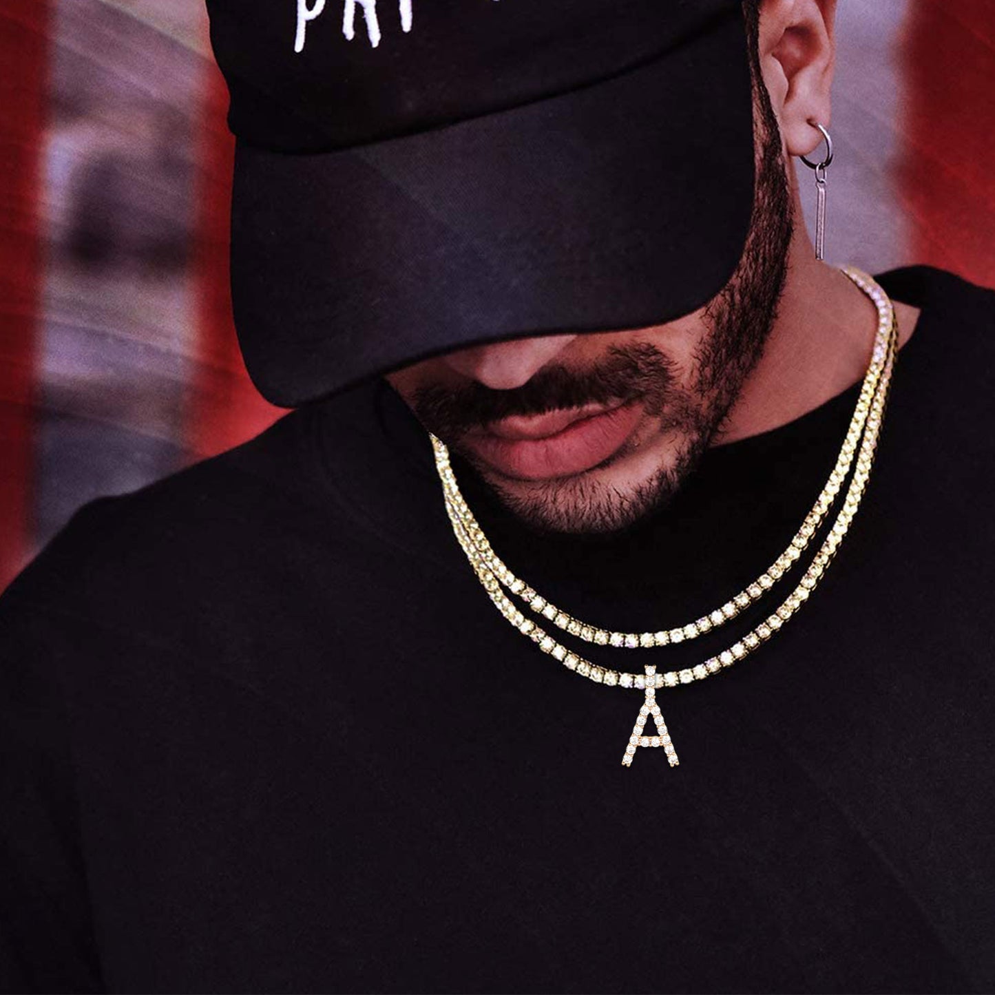 Male model styling bold initial pendant necklace over black A-shirt