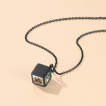 Black chain necklace with a cube pendant on a beige background