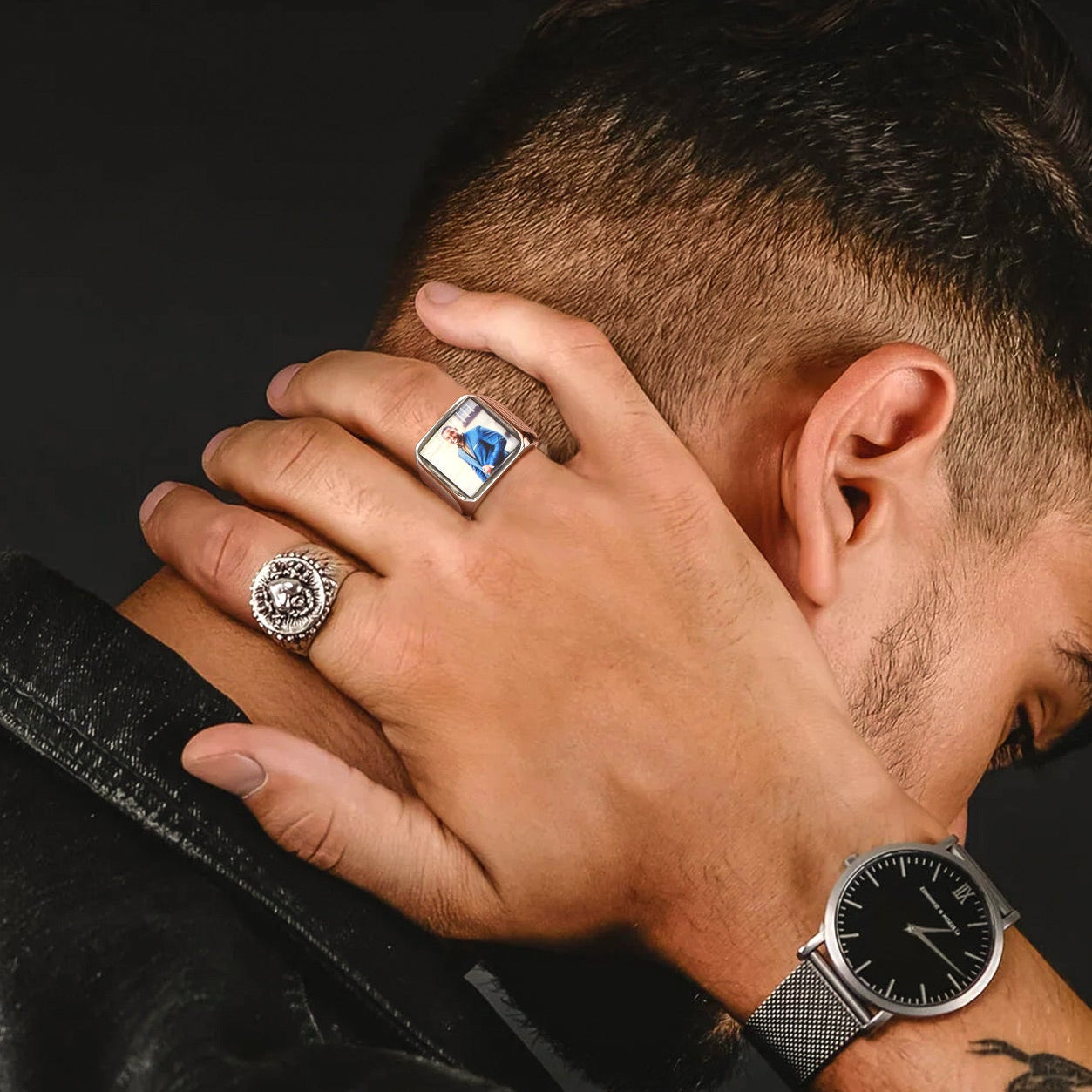 Man wearing a watch and rings with a dark background