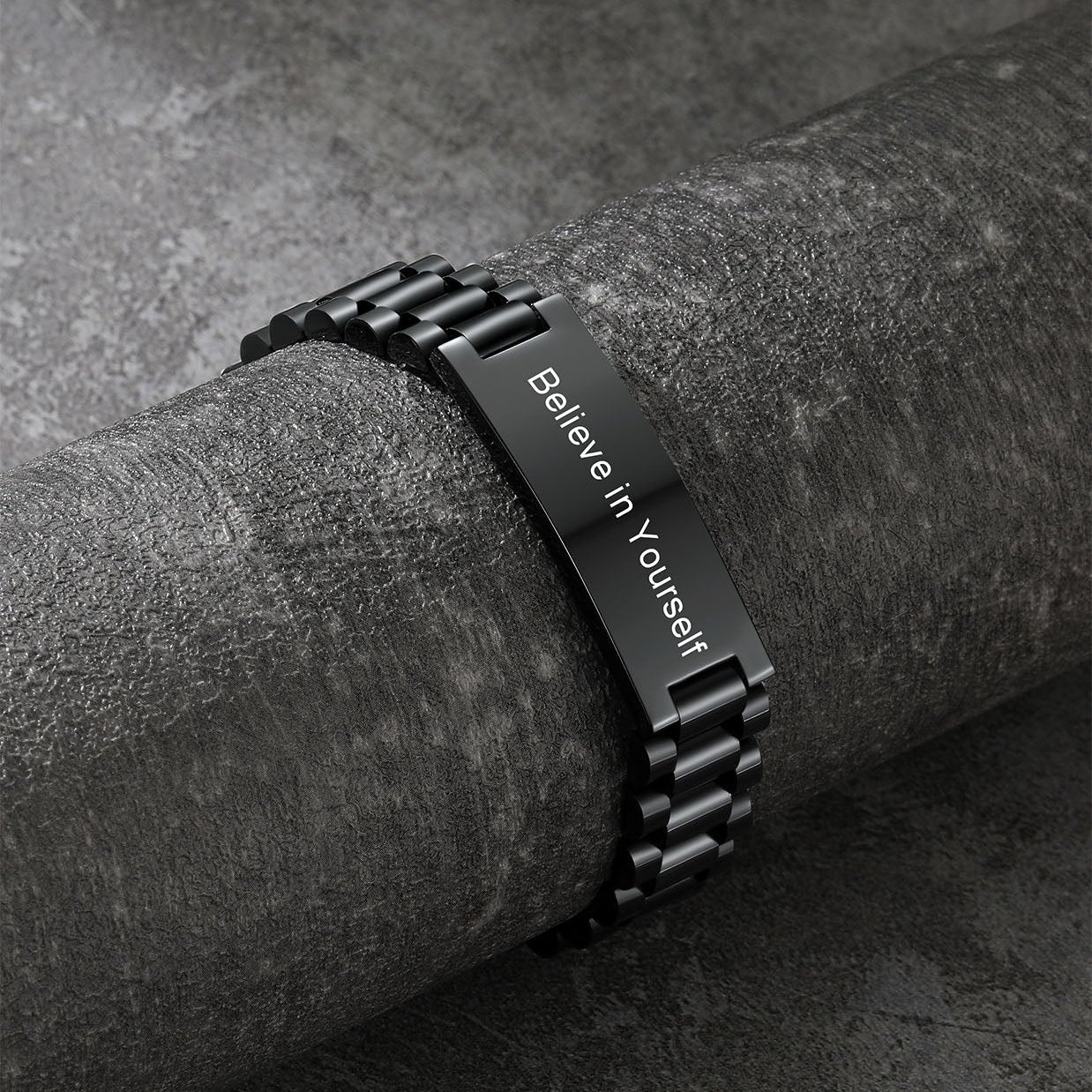 Black metal bracelet with 'Believe in Yourself' engraving on a dark surface