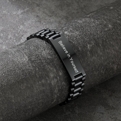 Black metal bracelet with 'Believe in Yourself' engraving on a dark surface